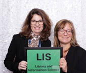 Two alumni holding the LIS sign.