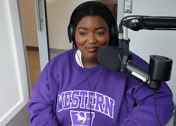 a female student presenting in front of a podcast mic