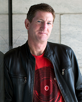 Headshot of David MacPherson in a black leather jacket and red shirt