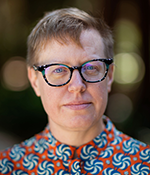 Headshot of Emily Drabinski in a patterned shirt with dark-rimmed glasses on