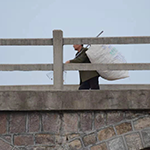Man crossing a bridge carrying a large sack.