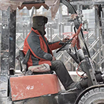 Man in winter clothes driving a forklift.