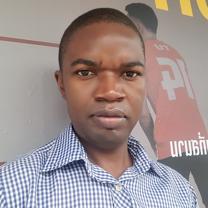 Headshot of Lovemore Dzikati wearing a blue and white checkered shirt.