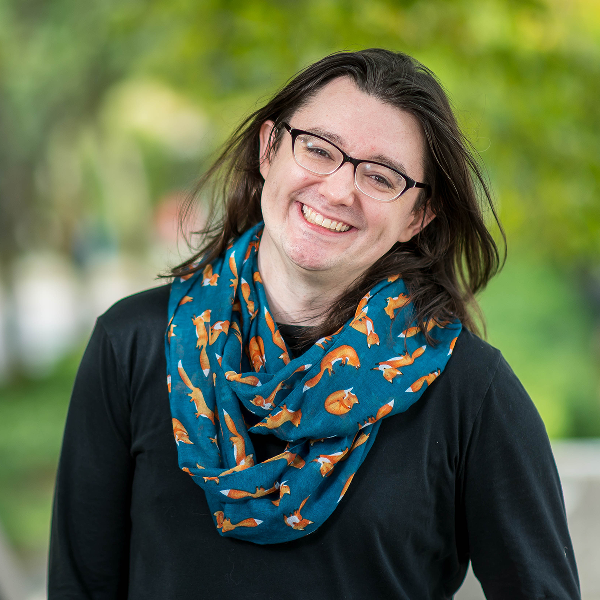Headshot of Bri Watson standing outside against greenery