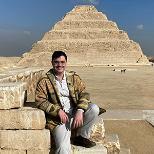 John Kausch sitting in front of a pyramid.