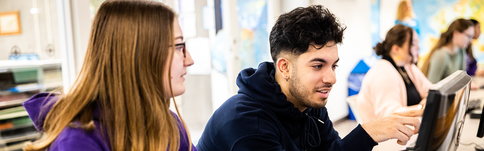 Two students sit and look at a computer together