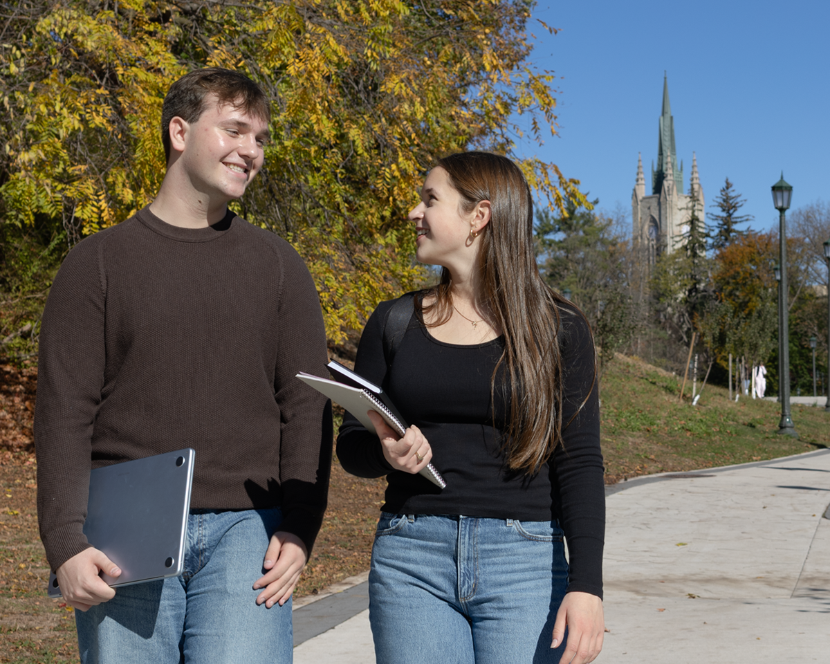 Students studying walking outside on campus in the fall.
