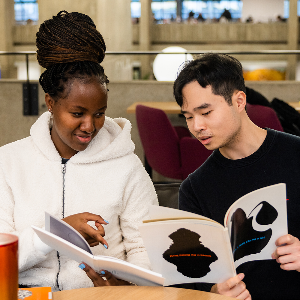 Two students looking through magazines together