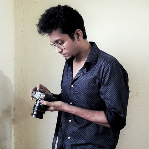 Santasil Mallik looking down at a camera in his hands.