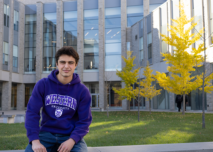 Student in a Western sweater sitting outside the FIMS & Nursing Building