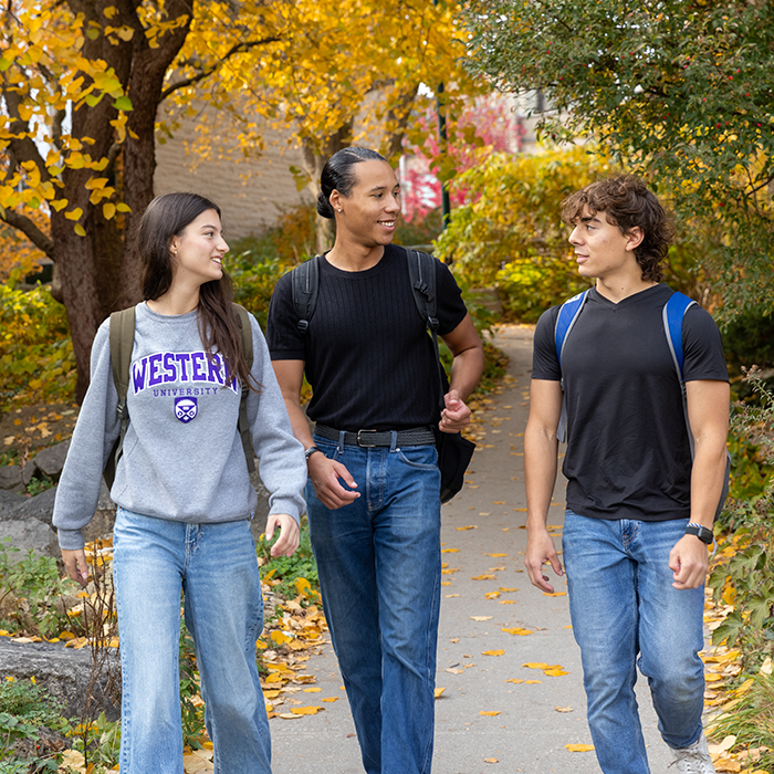 Three students walking outside on campus in the Fall.