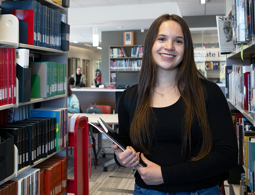 A student standing in the stacks of the FIMS Grad Library