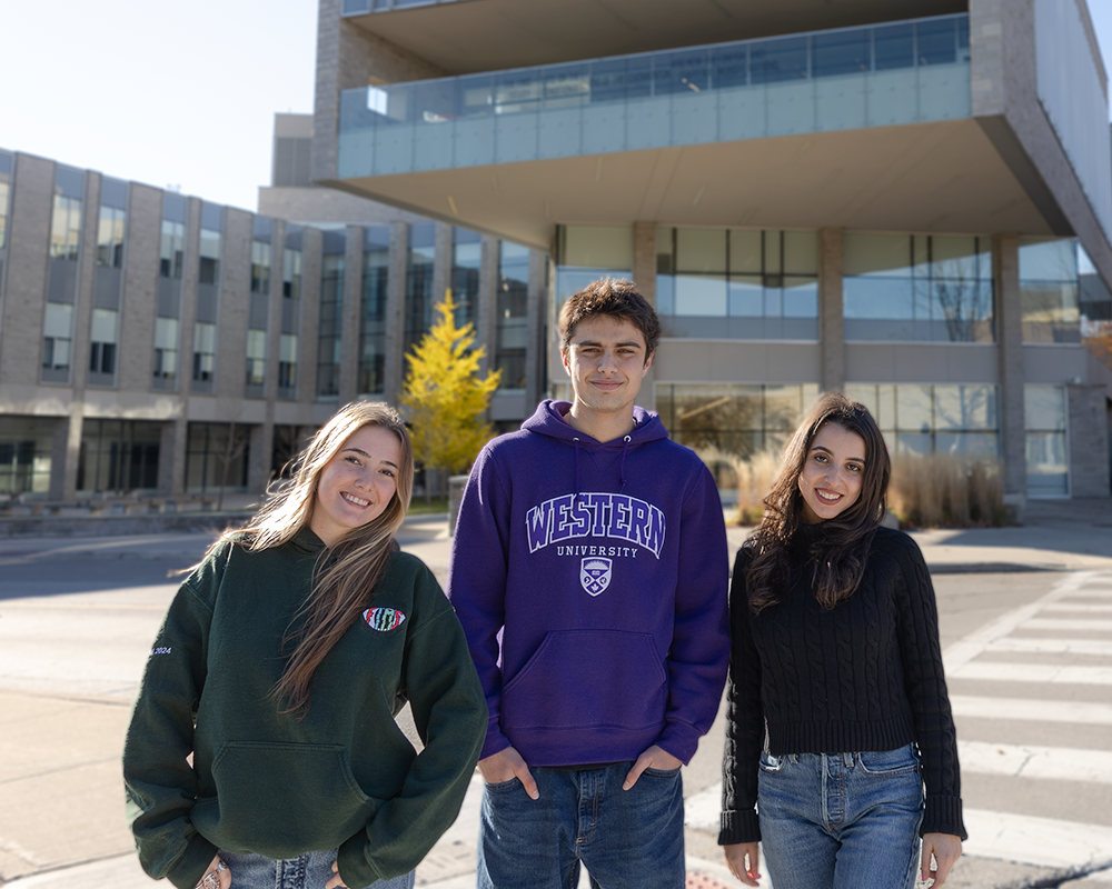 Three students standing in front of FNB in the sunshine.