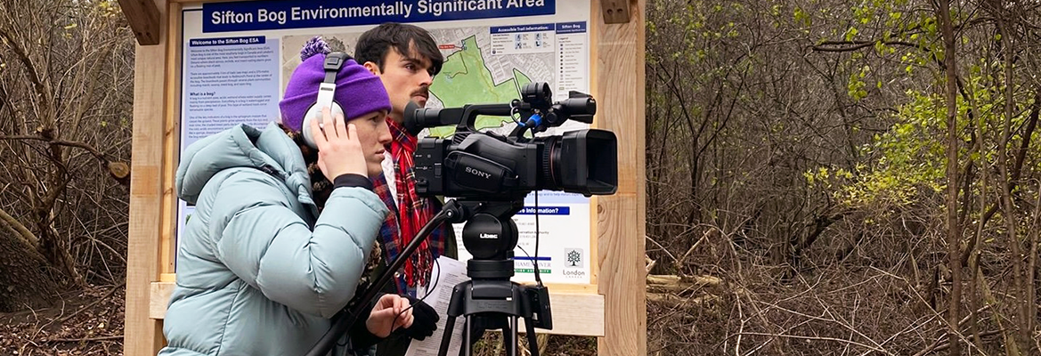 Students filming with a portable news camera outside in cool weather