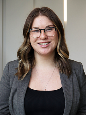 Photo of Emily Mackey in a black shirt and grey blazer