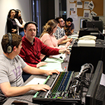 Student and staff work in the broadcast studio control room.