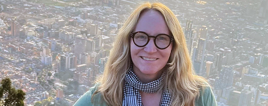 Photo of Amanda Grzyb standing with a large cityscape in the background.